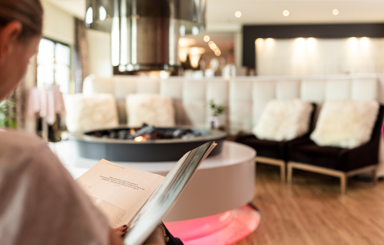 Eine Frau schaut in der Lounge des Hotels Seewirt Mattsee in die Karte