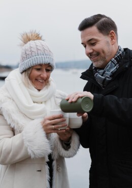 Ein Paar trinkt bei einem Winterspaziergang einen heißen Tee aus der Thermoskanne.