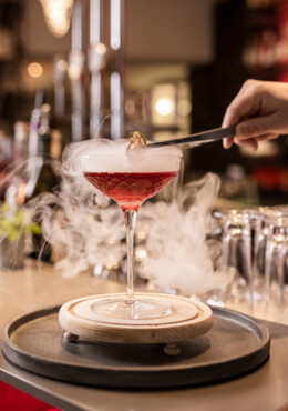 Ein rauchender Cocktail wird garniert