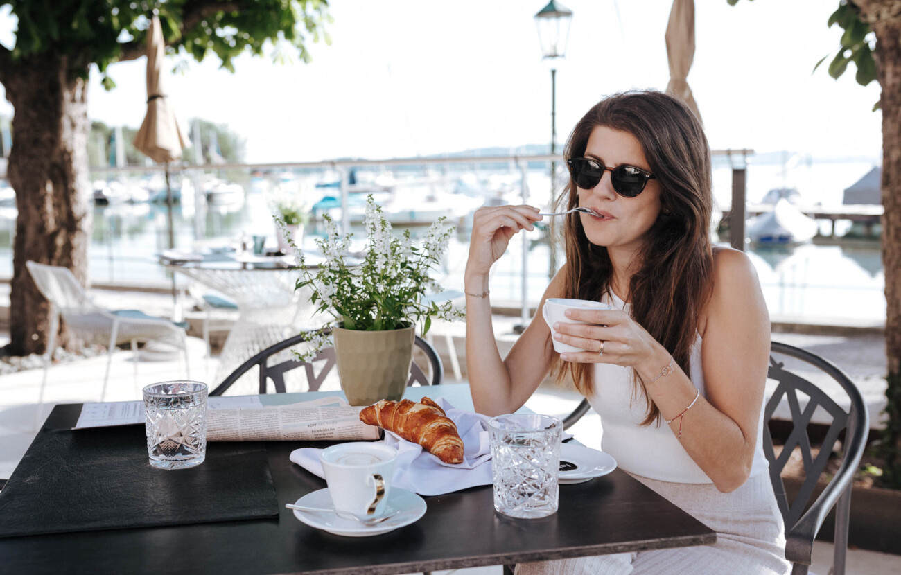 Eine Frau sitzt auf der Terrasse und trinkt einen Kaffee im Hotel Seewirt Mattsee