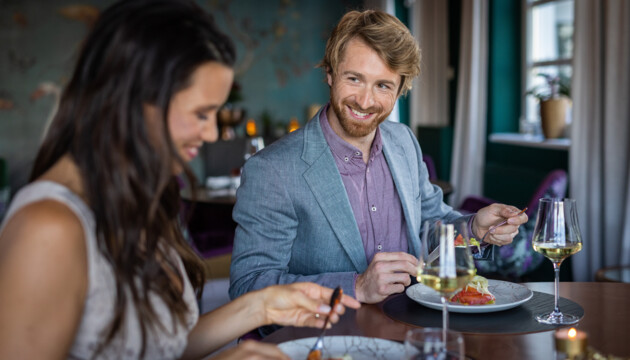 Ein Paar genießt ein elegantes Abendessen im Seewirt Mattsee mit Wein und stilvollem Ambiente.