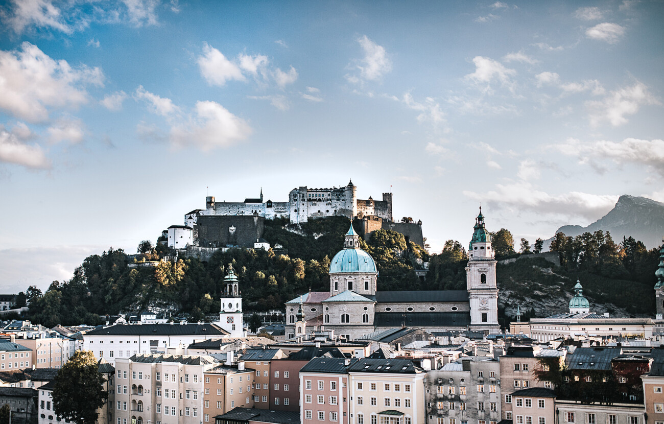 Salzburgs Altstadt mit Festung Hohensalzburg im Hintergrund unter blauem Himmel.