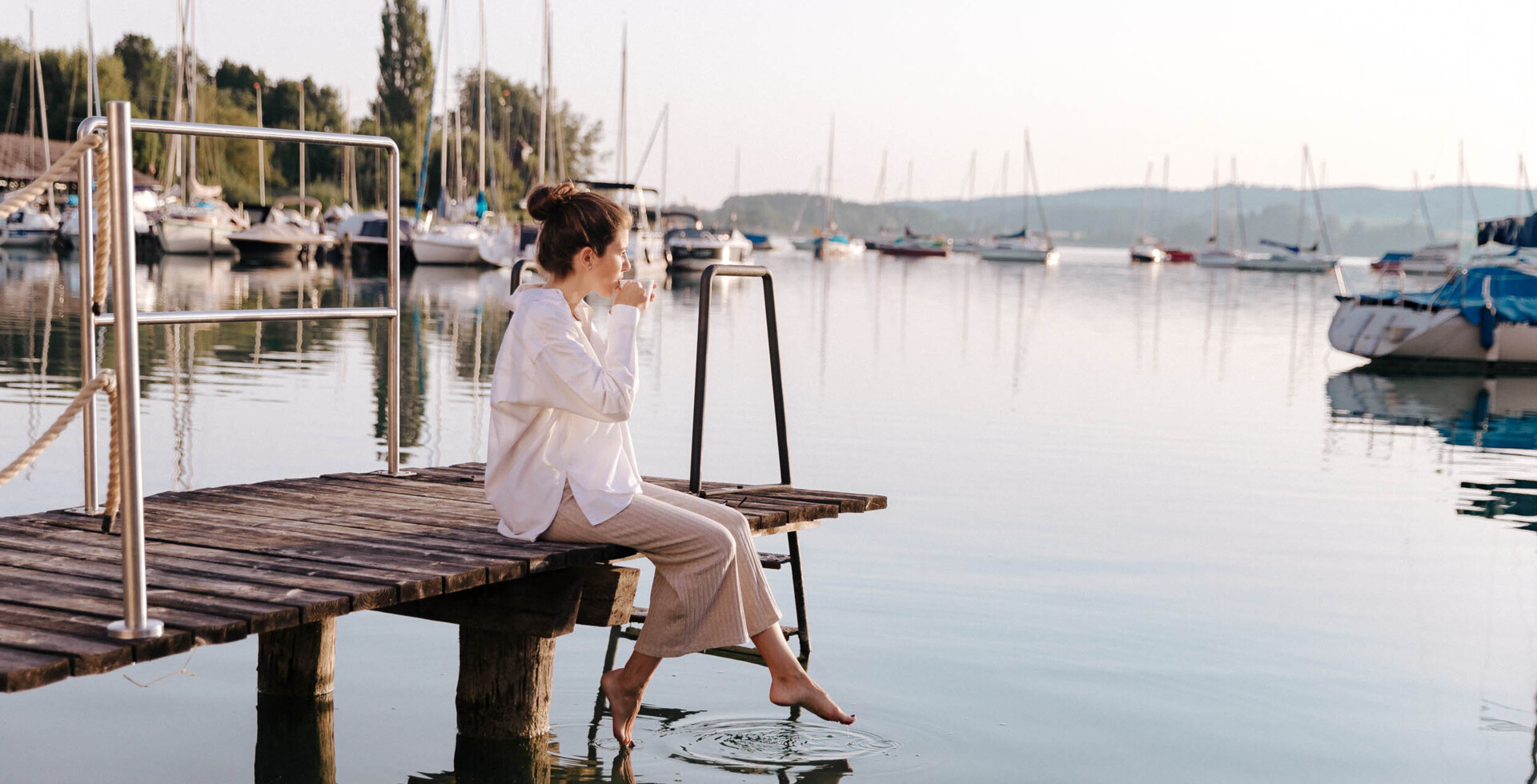 Frau sitzt am Steg mit Blick auf den Mattsee