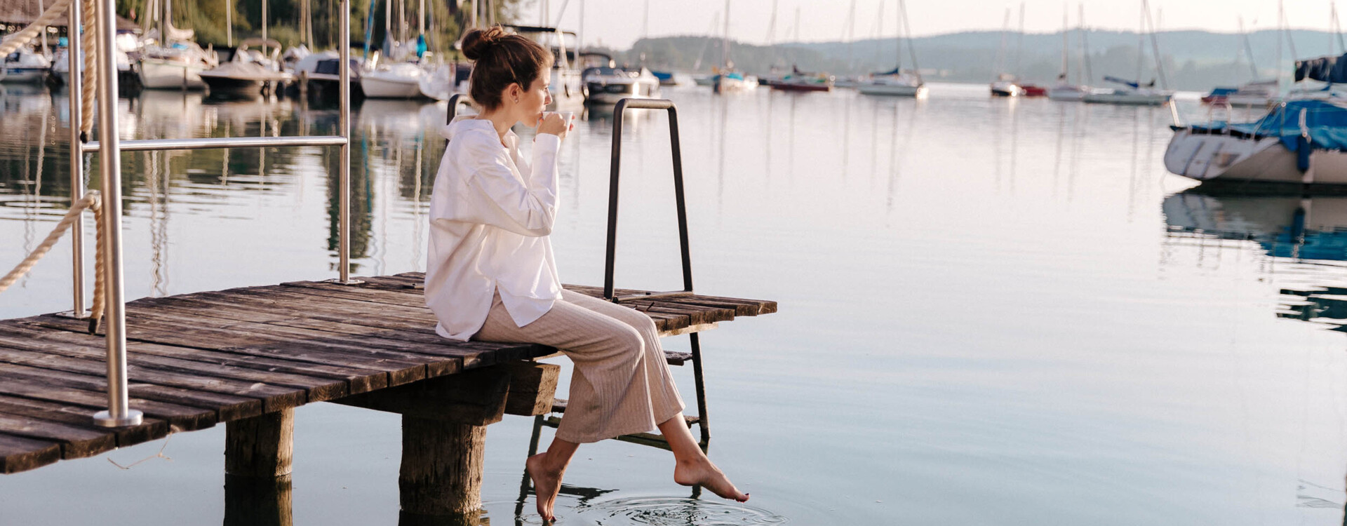 Frau sitzt am Steg mit Blick auf den Mattsee