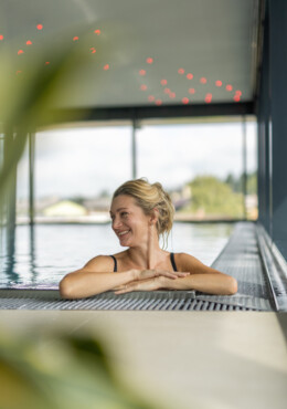 Eine Frau entspannt sich im Innenpool mit Blick auf die Landschaft im Hotel Seewirt Mattsee.