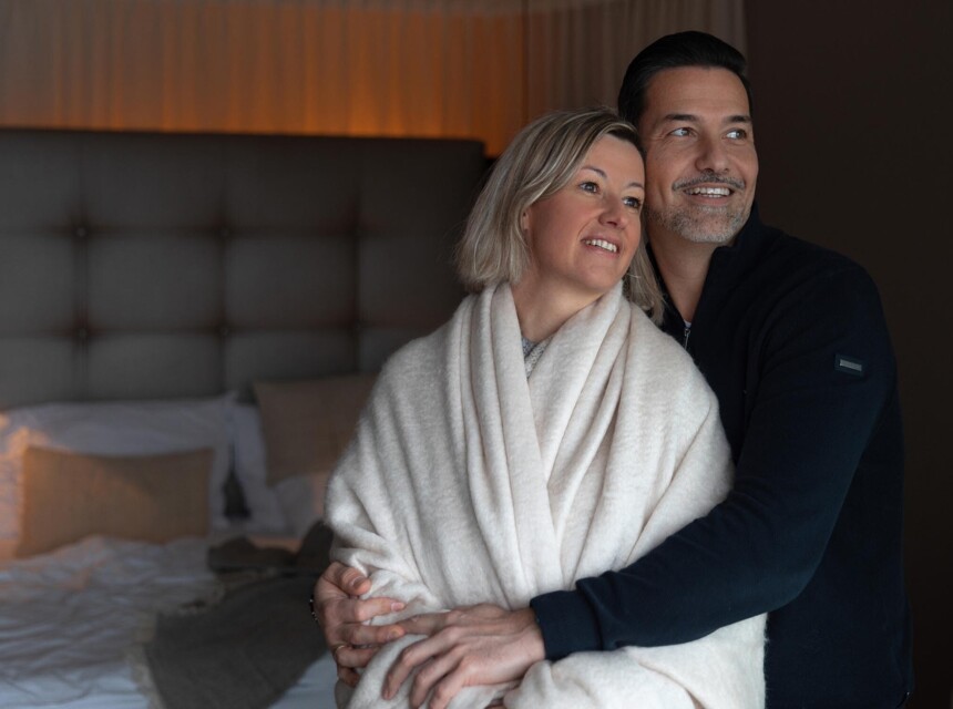 Ein junges Paar kuschelt im Zimmer und schaut auf den See