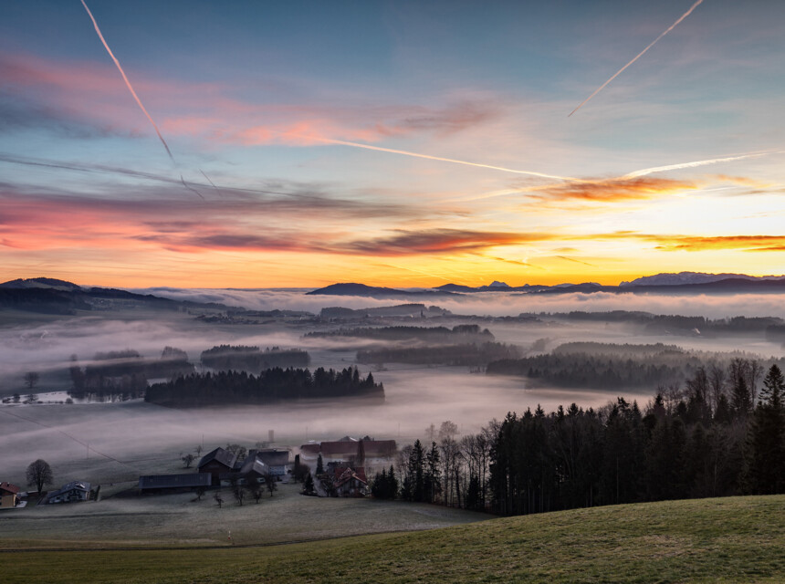 Sonnenaufgang über nebliger Landschaft mit Wäldern und Hügeln in der Nähe von Seewirt Mattsee.