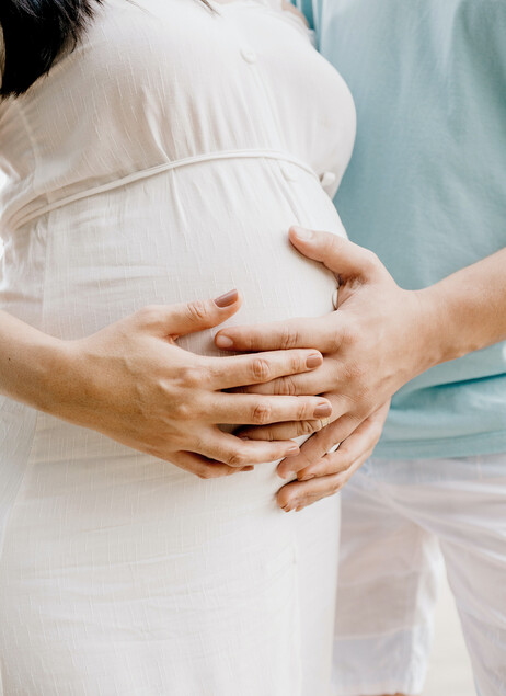 Ein Paar hält liebevoll den Babybauch der Frau in Händen