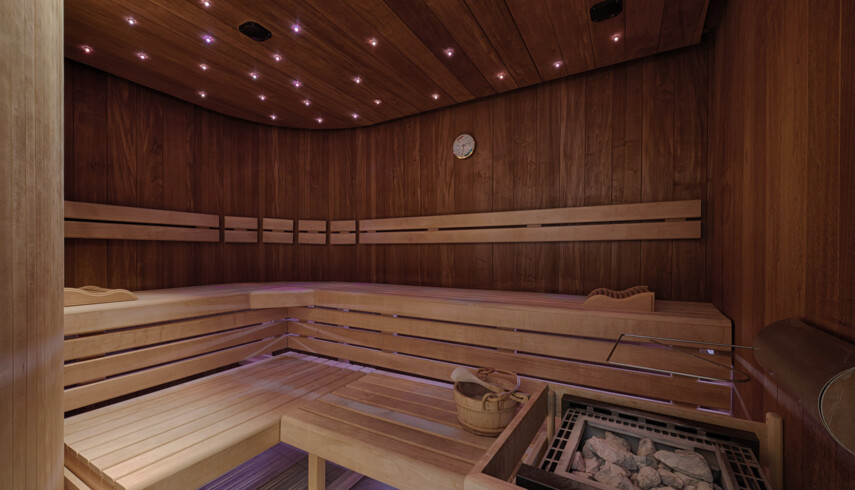 Geräumige Sauna mit Holzbänken und Steinen, warme Beleuchtung an der Decke; ideal für Entspannung im Seewirt Mattsee.