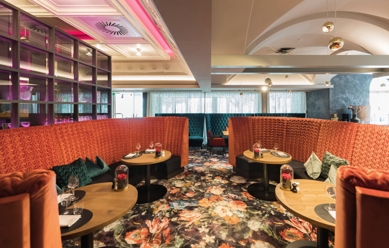 Elegantes Restaurant mit geblümtem Teppich und stilvollen Sitznischen im Seewirt Mattsee Hotel.