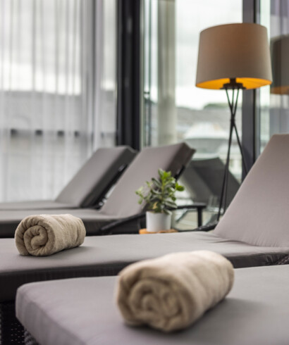 Liegestühle mit Handtüchern und Pflanze in einem stilvollen Spa-Bereich im Seewirt Mattsee Hotel.