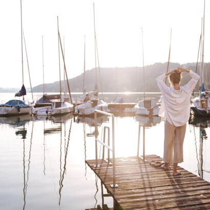 Frau am See auf Steg und Booten
