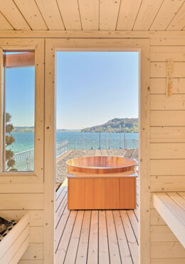 Innenansicht einer Sauna mit Blick auf einen Whirlpool und den Mattsee im Hintergrund bei Seewirt Mattsee.
